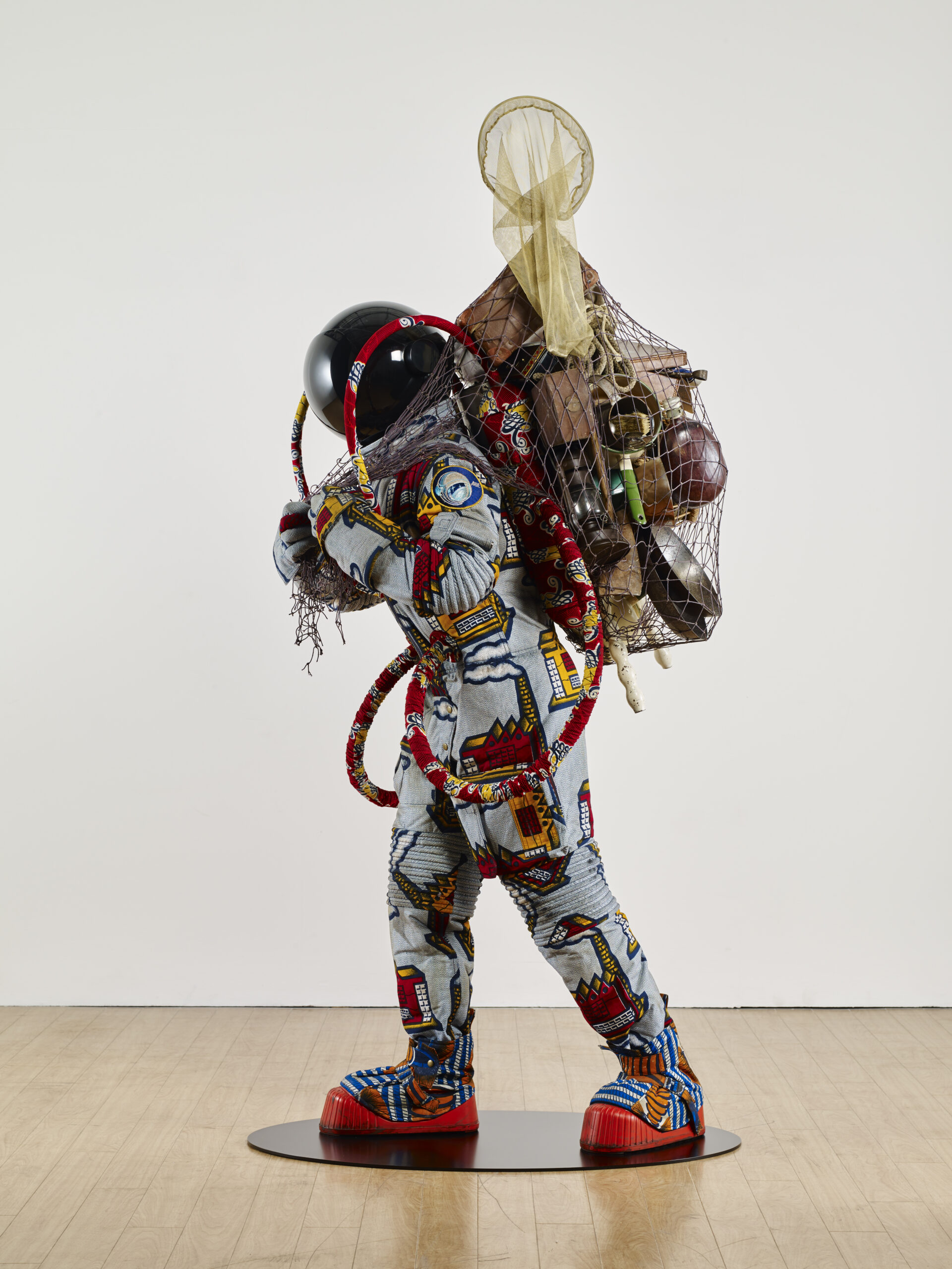 Yinka Shonibare (London, England, 1962 - Lives in London) Refugee Austronaut II (2016) Fibreglass mannequin, Dutch wax printed cotton textile, net, possessions, astronaut helmet, moon boots and steel baseplate 210 x 90 x 103 cm Courtesy the Artist and James Cohan Gallery, New York / Photo Stephen White & Co. / © Yinka Shonibare CBE